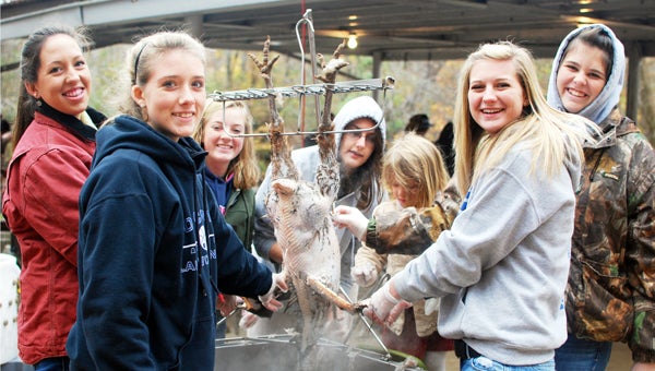 Yancy Pace, Brittany Jones, Olivia Clayton, Taylor Jones, Margaret-Mary (child), Cheyenne Johnson and McKenzie Rice dunk a turkey to loosen its feathers before plucking them by hand. (photo submitted by Ashley Gilbert)