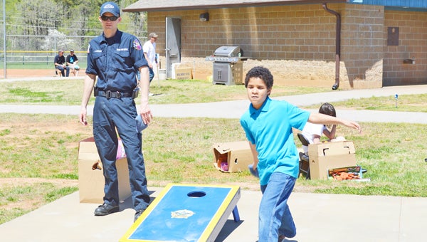 Brandon West plays corn hole at Polk County’s first Child Abuse Awareness Day held at the Polk County Recreation Park in Mill Spring on Saturday, April 13 as Saluda Fire and Rescue fireman Nick Edwards helps. Visit www.tryondailybulletin.com for more photos of the event. (photo by Leah Justice)