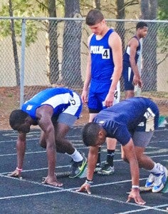 Polk’s Matthew Darden holds the blocks for Anthony Carson set to race the 100 Meter Dash at the FCA meet at AC Reynolds. (photo by Jenny Wolfe)
