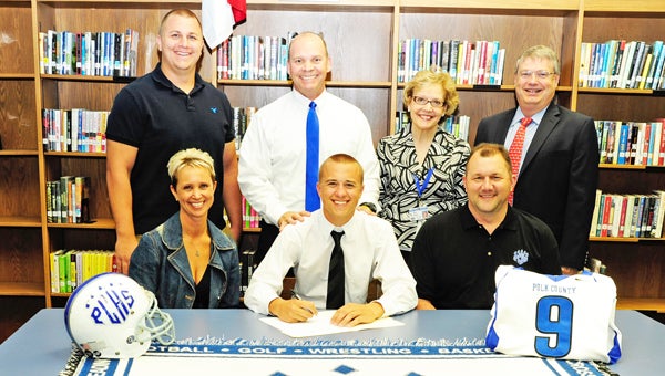 Polk County High School senior and three-sport athlete Alec Philpott, center, is shown Wednesday, May 15 signing with Lenoir-Rhyne University. He’s flanked by parents, Kelli and Todd. Back row, from left: Alec’s older brother Tyler Philpott, Wolverines’ head football coach Bruce Ollis, PCHS Principal Mary Feagan and Polk County School Superintendent Bill Miller. (photo by Mark Schmerling)