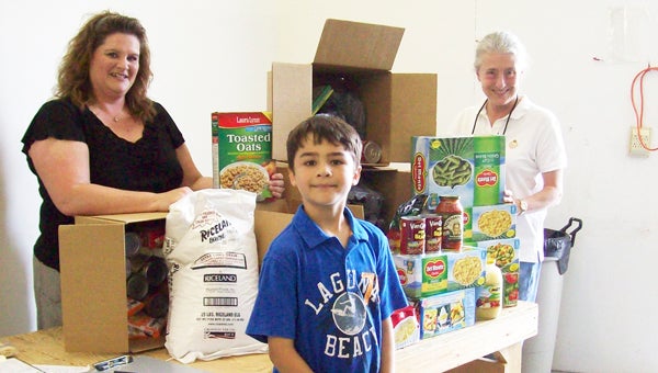 Instead of asking for the typical toys, games or sports equipment that 8-year-olds usually put at the top of their birthday wish-list, Kaden Powell asked his friends and family for food for his birthday. Powell requested the  food to donate to Thermal Belt Outreach Ministry’s (Outreach’s) food pantry.  Because of Powell’s generosity, Outreach received more than 100 pounds of vegetables, cereal, rice, spaghetti sauce and other pantry staples. Shown left to right, Michelle Reedy, Outreach Client Service Manager; Kaden Powell; and Carol Newton, Outreach executive director.) 