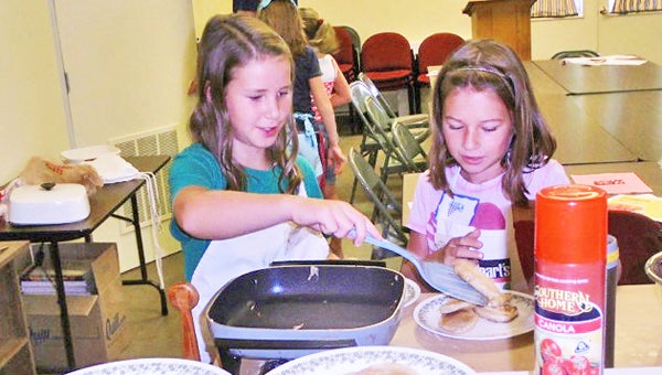 This summer Polk County youth had the opportunity to learn all about the world of cooking. They were able to name all of the cooking tools and work with many of them while they cooked their own breakfast, lunch and dinner. “Which all turned out tasty and wonderful,” said Helen Clark,4-H agent.  In addition, they learned about food safety and not only how to prepare a meal but how to make the meal nutritionally balanced. Elsie Padgett and Sydney Hosinger, right, participate in the 4-H beginner cooking class. (photo submitted by Helen Clark)
