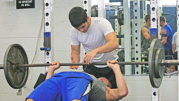 Polk County High School football player Anthony Marino spots as teammate Storm Wheeler bench presses 185 pounds during a recent workout in the weight room. PCHS players are under a dead period this week before hitting the weight room again next week. The Wolverines will host their annual jamboree against E. Rutherford, Chase and N. Henderson at 6 p.m. Aug. 12. The border showcase is Aug. 16 and PCHS’ first regular season game is Aug. 23 versus Shelby. (photo by Virginia Walker)