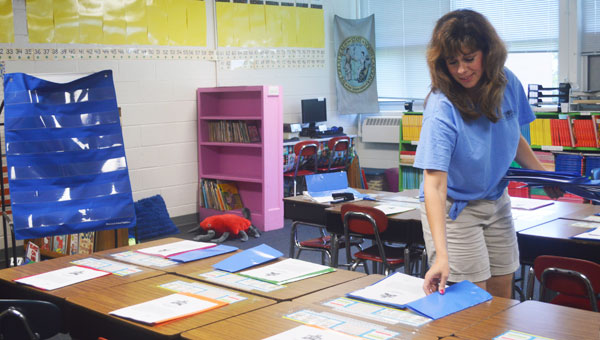 Michelle Richardson is returning for her first year back in the classroom after taking several years off to raise her daughters. Richardson is seen here passing out folders to each desk in her second-grade classroom at Polk Central. (photo by Samantha Hurst)