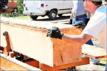 Chris Carroll works with a piece of lumber at the mobile sawmill he and wife, Amy, use in their mobile business. 