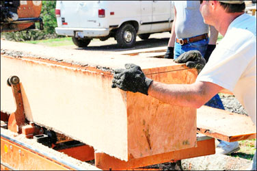 Chris Carroll works with a piece of lumber at the mobile sawmill he and wife, Amy, use in their mobile business.