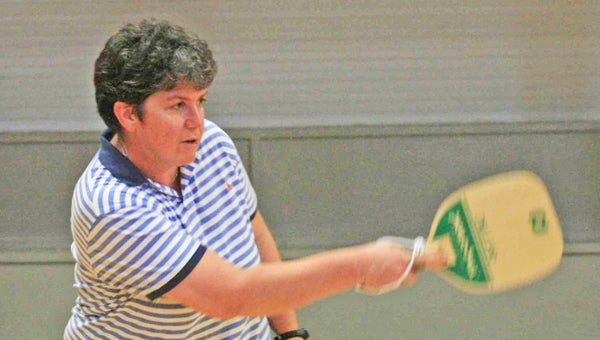 Players are batting around a new sport at the Polk County Recreation Department. Last week, in Stearn’s Gym, Anne Howe introduced several area residents to Pickleball. This sport, similar to tennis, is played on a badminton court with the net lowered to 34 inches at the center. It is played with a perforated plastic baseball (similar to a whiffle ball) and wood or composite paddles, according to the USA Pickleball Association. Shown at left is Howe leading instruction. Middle, Dawn Blanton takes her turn at the game and Debbie Pegg, right, said the game was easier to learn than she thought it would be. (photos by Virginia Walker)