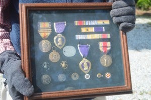 Blayne McMurray proudly holds a shadow box displaying the medals and commendations he received after being seriously injured in World War II. (photo by Samantha Hurst)