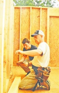 Lee Cobourn and another Habitat volunteer measure out framework inside a recent home built for a local family. 