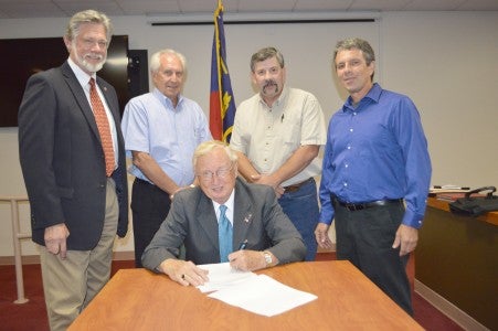 Polk County Commissioners signed the county’s new economic development plan and strategy following approval of the plan on Monday, Aug. 18. Pictured are Robert Williamson (left), consultant for the plan and now the county’s interim economic development director, commissioner Keith Holbert, commissioner Tom Pack, commissioner Michael Gage and commissioner chair Ted Owens (sitting). (photo by Leah Justice)