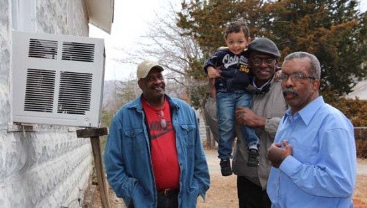 From left, Edward Hines, husband of Rev. Arby Hines, together with Rev. Searight and Gerald Petty walk the perimeter of the church discussing needed updates, including central air conditioning to replace two window units. Rev. Searight is holding RJ Hamilton, 2. 