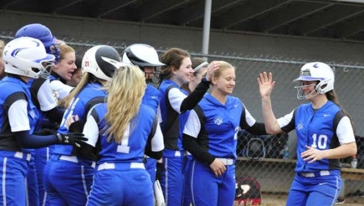 Polk County's Hayley Kropp has enjoyed some fine moments in both basketball and softball, but this swing produced memorable results-- a grand slam home run, to give the Wolverines an 11-0 lead over Hendersonville, at Columbus last Thursday. Her teammates gathered near home plate to give her a hero's welcome. (Photo by Mark Schmerling)