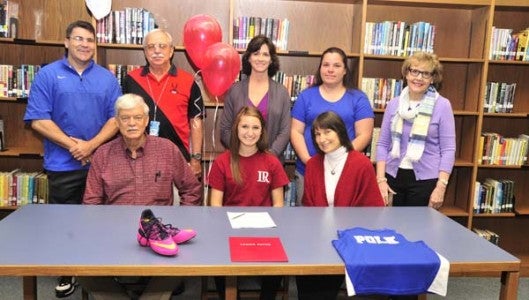 Mesa, Arizona's loss has been Polk County High School's gain, as cross country and track standout Allison Swope (front row, center), who moved here last year, starred for the Wolverines as a senior, and is now off to run for Lenoir-Rhyne University on a scholarship. On April 17, Swope signed her intent to attend and compete for, Lenoir-Rhyne. Swope is flanked by her mom, Cathy Arnold and her stepdad Dave Arnold. Back row, from left: PCHS Director of Athletics Jeff Wilson, Head Cross Country and Track Coach Alan Peoples, Assistant Cross Country and Track Coach Jenny Wolfe, Assistant Track Coach Amanda Simoncic, and PCHS Principal Mary Feagan. (Photo by Mark Schmerling)